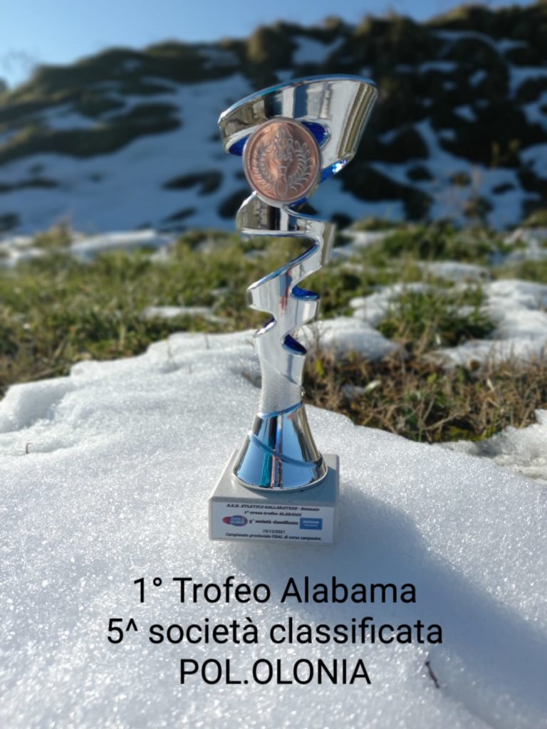 Foto del trofeo con targhetta di quinta società classificata appoggiato su un prato parzialmente ricoperto di neve.