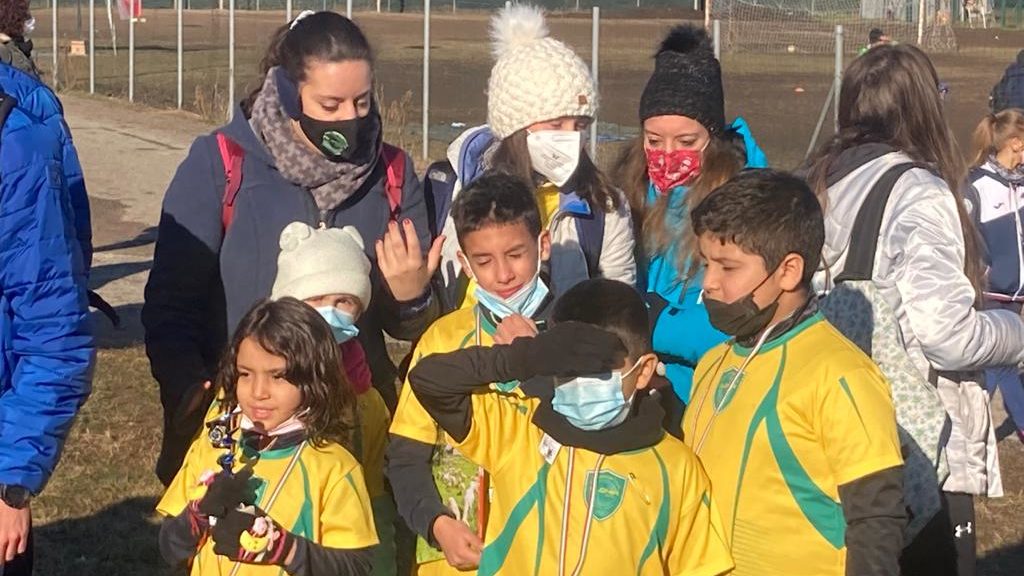 Foto di un gruppo di cinque atleti in divisa giallo-verde e tre allenatrici con il trofeo