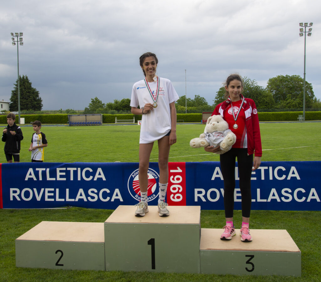 Agnese Sardi con la maglietta bianca di campionessa provinciale sul gradino più alto del podio del salto in alto